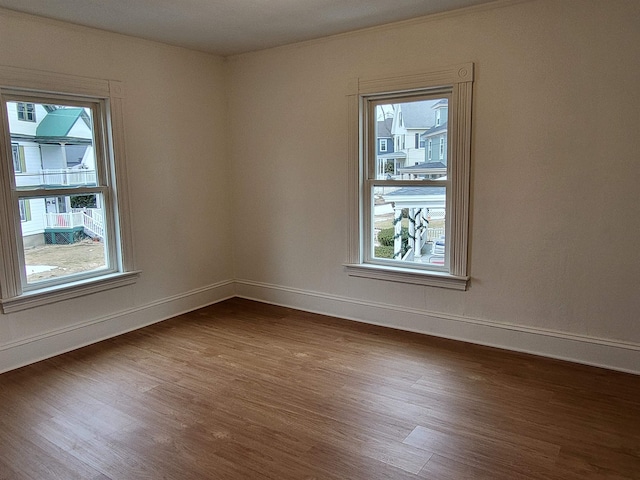 empty room featuring a wealth of natural light, baseboards, and dark wood-style floors