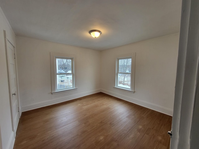 unfurnished room featuring baseboards and dark wood-type flooring