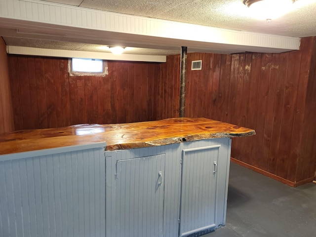 bar featuring indoor wet bar, visible vents, wood walls, and a textured ceiling