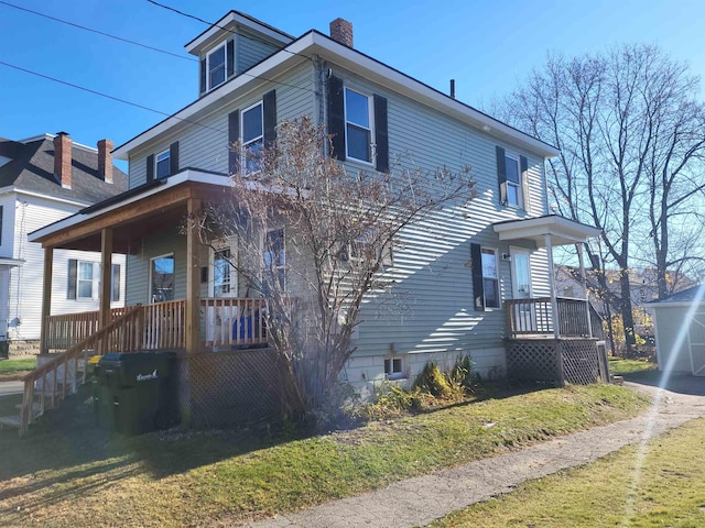 view of side of home featuring a porch, a yard, and a chimney