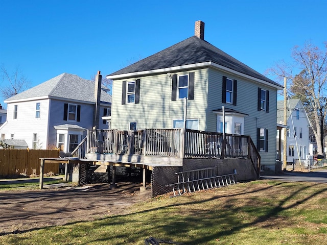 back of property featuring a deck, a yard, fence, and a chimney