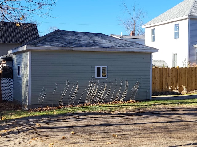 view of side of home with roof with shingles and fence