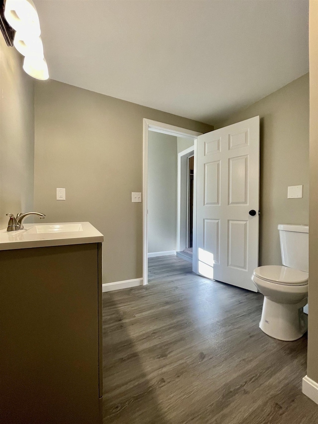 bathroom featuring toilet, vanity, baseboards, and wood finished floors