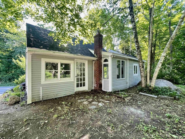 back of property with roof with shingles and a chimney