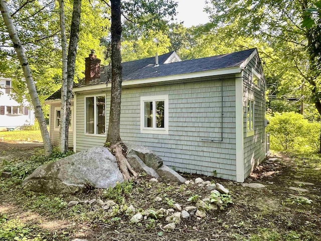 exterior space with a chimney and a shingled roof