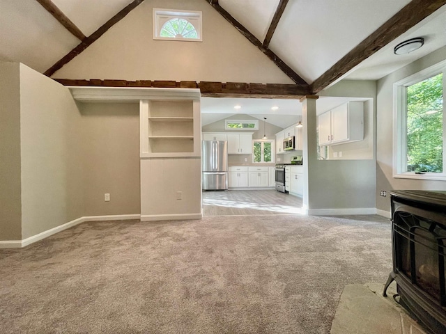 unfurnished living room with baseboards, beam ceiling, light colored carpet, and plenty of natural light