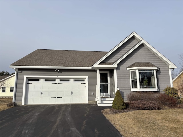 single story home featuring driveway, a garage, and roof with shingles