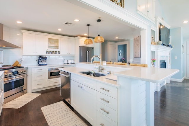 kitchen featuring visible vents, a sink, light countertops, high end appliances, and dark wood-style flooring