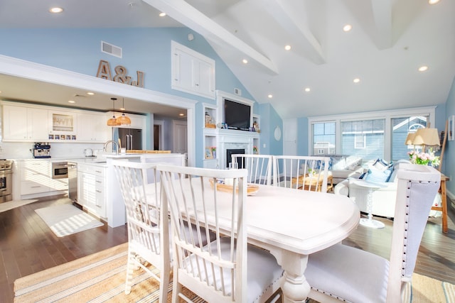 dining area with beamed ceiling, a fireplace, visible vents, and light wood-type flooring