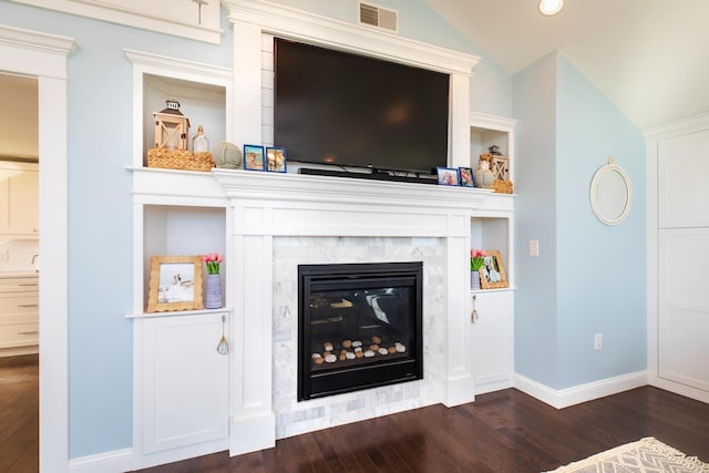 interior details featuring a glass covered fireplace, wood finished floors, visible vents, and baseboards