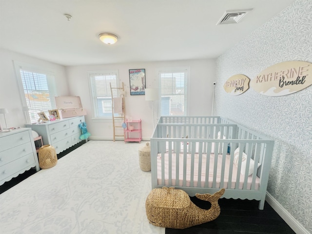 bedroom featuring wallpapered walls, a crib, baseboards, and visible vents