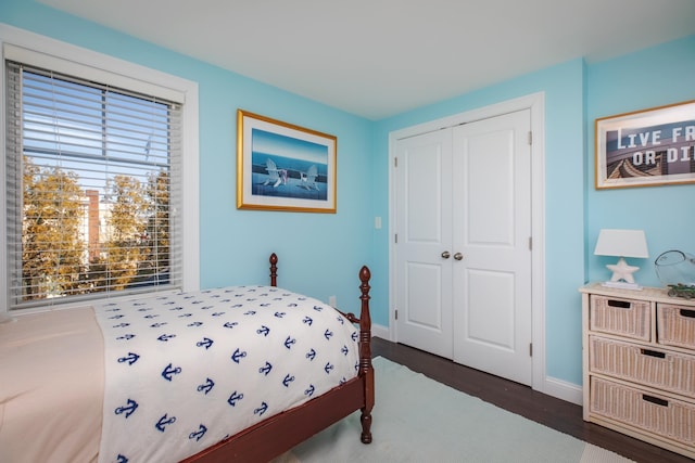 bedroom featuring a closet, baseboards, and dark wood-type flooring