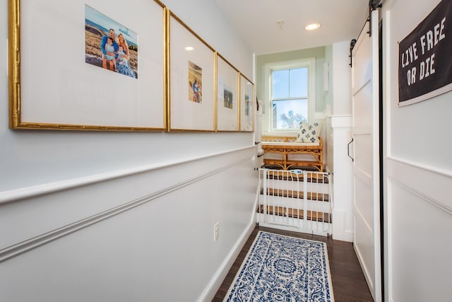 hallway featuring recessed lighting, a barn door, and wood finished floors