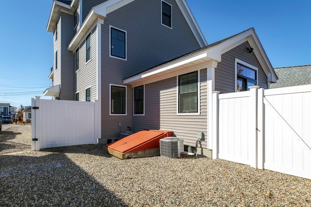 rear view of property featuring fence and central AC