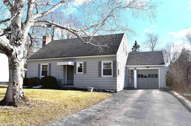 view of front of property featuring roof with shingles, a front yard, a chimney, a garage, and driveway