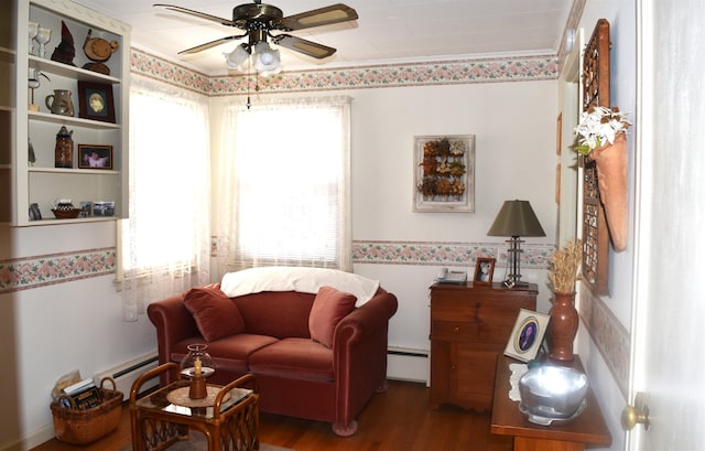 living area with baseboard heating, crown molding, ceiling fan, and wood finished floors