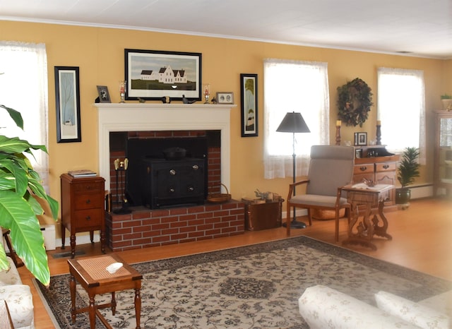 living area featuring a brick fireplace, wood finished floors, and crown molding