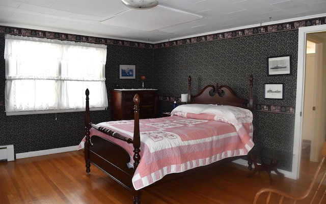 bedroom with wallpapered walls, wood finished floors, and baseboards