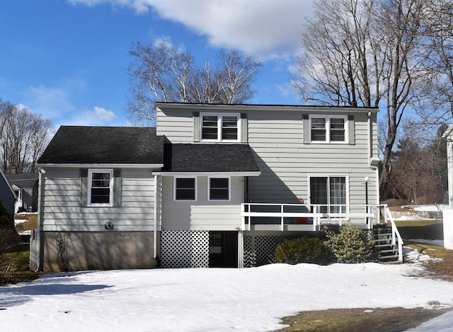 traditional home featuring a deck and a shingled roof