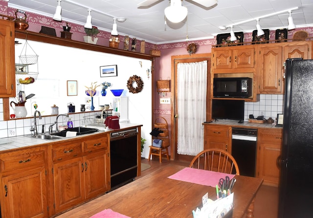 kitchen with light wood-type flooring, black appliances, a sink, backsplash, and tile countertops