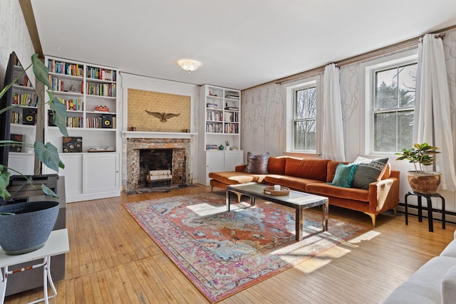 living area with a baseboard radiator, a brick fireplace, and hardwood / wood-style floors