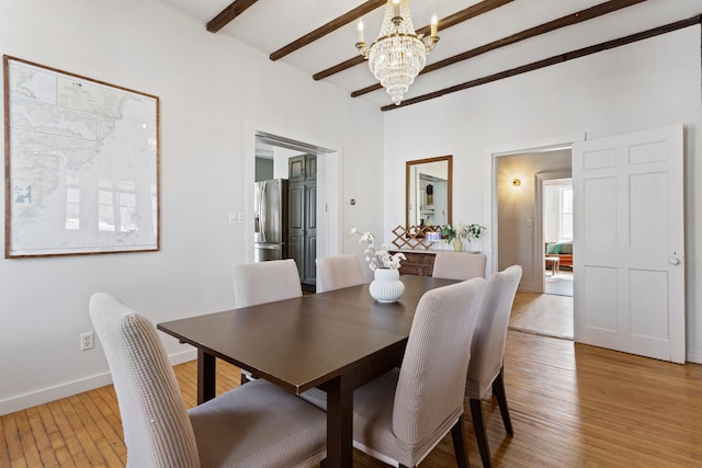 dining space with light wood-type flooring, beamed ceiling, baseboards, and a chandelier