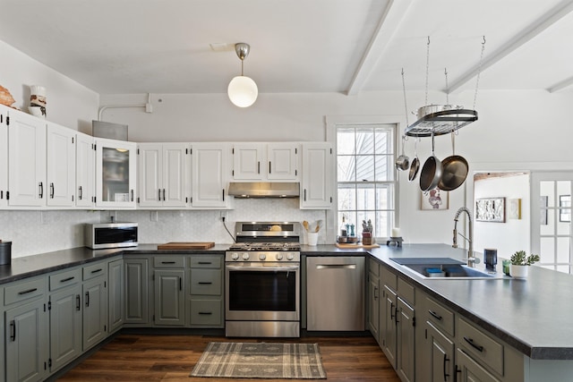 kitchen with a peninsula, a sink, stainless steel appliances, white cabinets, and under cabinet range hood