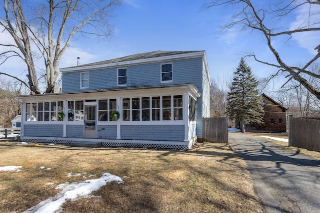 view of front of home with fence, a gambrel roof, and a sunroom