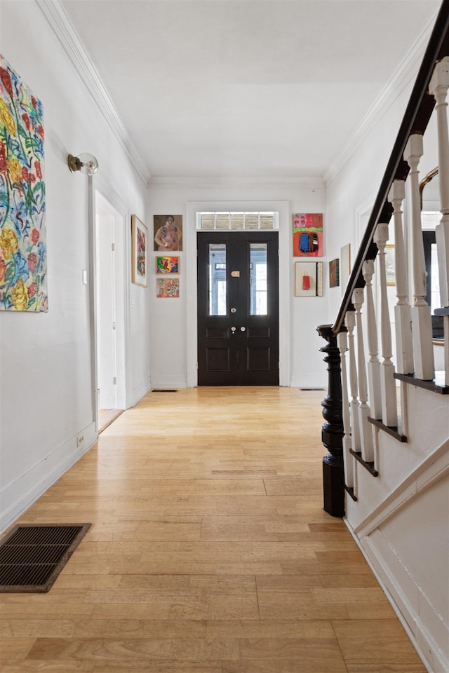 entrance foyer featuring visible vents, stairs, light wood-type flooring, and ornamental molding