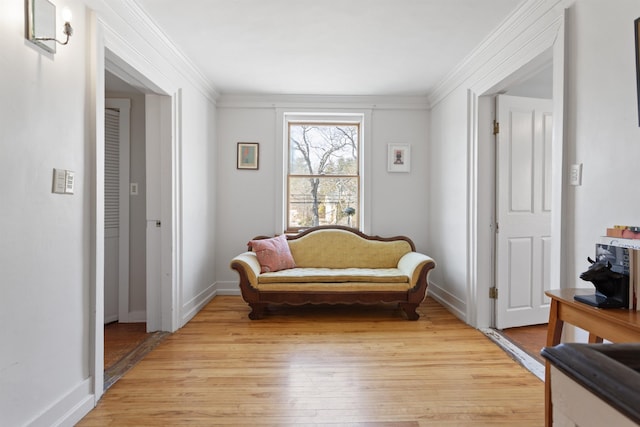 sitting room with baseboards, crown molding, and light wood finished floors