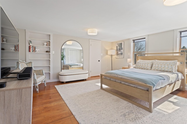 bedroom with light wood-style flooring and arched walkways