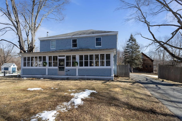 rear view of house featuring fence and a sunroom