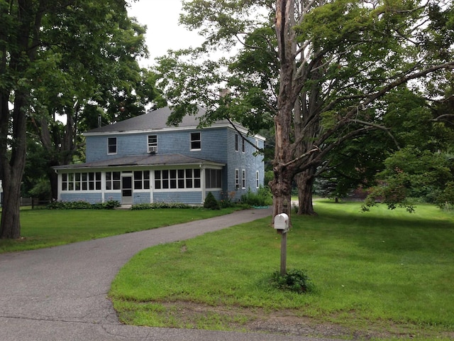 farmhouse inspired home featuring a front lawn and a sunroom