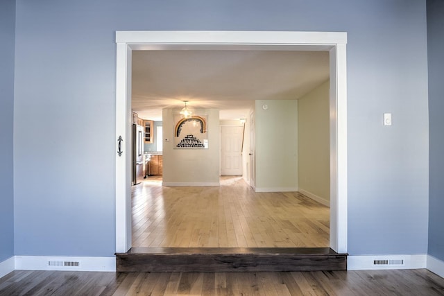 corridor featuring baseboards, visible vents, and wood-type flooring