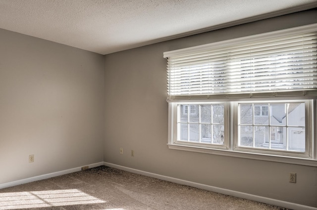 carpeted spare room with baseboards and a textured ceiling