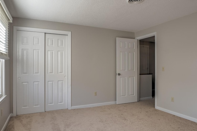 unfurnished bedroom featuring baseboards, carpet floors, a textured ceiling, and a closet