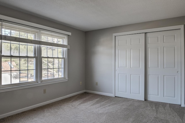 unfurnished bedroom with carpet flooring, baseboards, a closet, and a textured ceiling