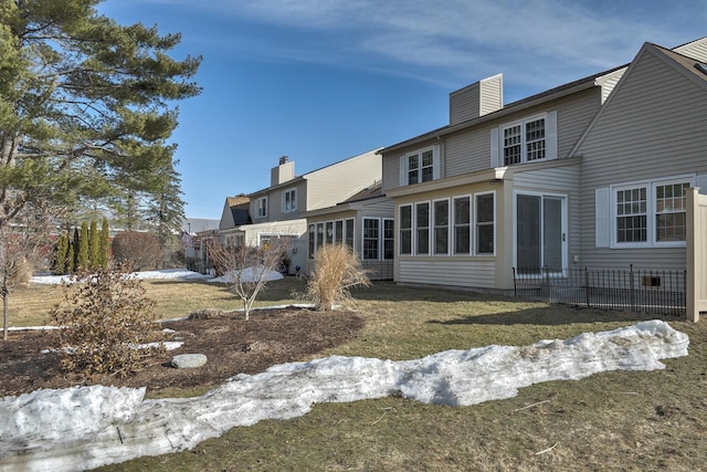 rear view of property featuring a lawn, a sunroom, and a chimney