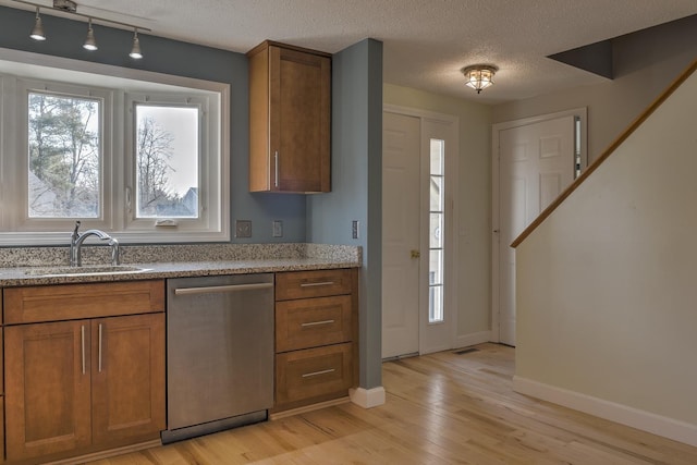 kitchen featuring dishwasher, brown cabinetry, and a sink