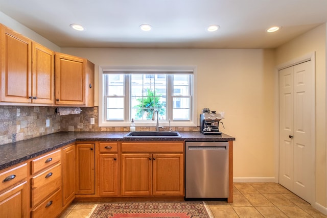 kitchen featuring light tile patterned flooring, a sink, backsplash, and stainless steel dishwasher