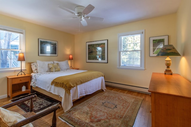 bedroom with wood-type flooring, a ceiling fan, and baseboard heating