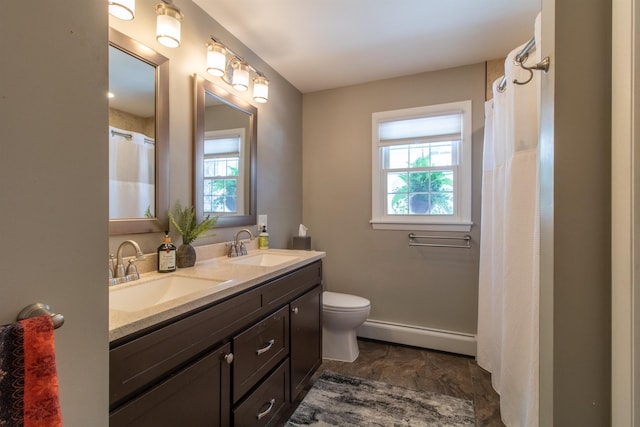 full bath with double vanity, baseboard heating, toilet, and a sink