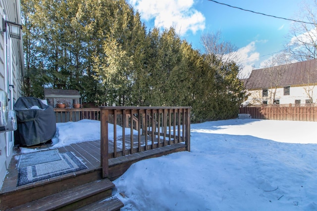 yard covered in snow with a wooden deck and fence