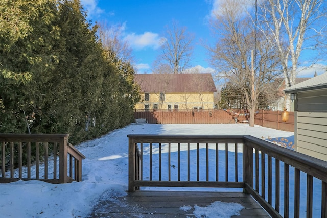 snow covered deck with a fenced backyard