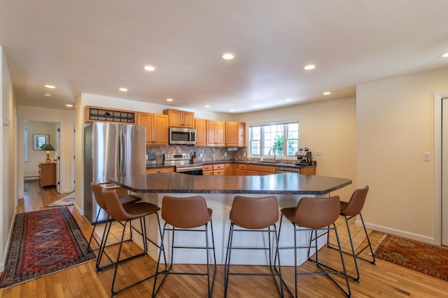 kitchen featuring dark countertops, decorative backsplash, appliances with stainless steel finishes, and a sink