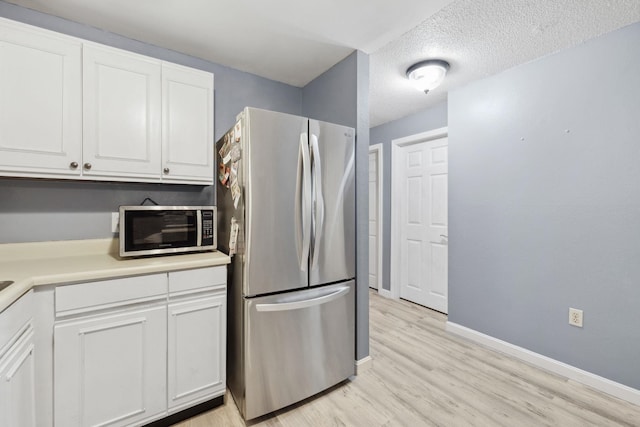 kitchen with baseboards, light countertops, light wood-style floors, white cabinets, and stainless steel appliances