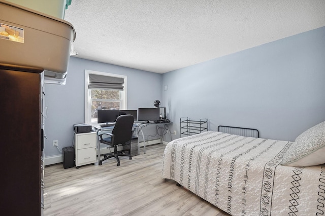 bedroom featuring baseboards, a textured ceiling, and wood finished floors