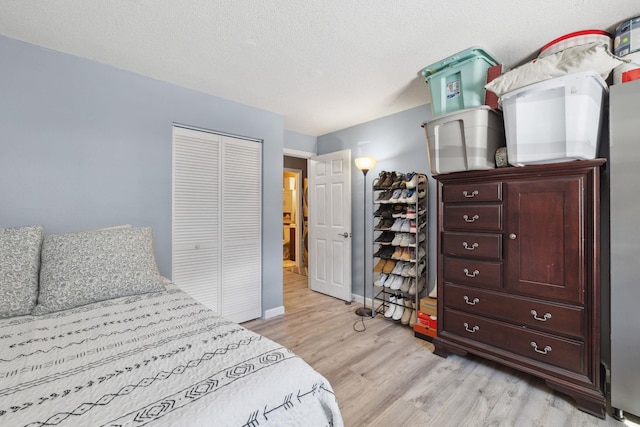 bedroom featuring light wood-style flooring, baseboards, a closet, and a textured ceiling