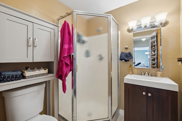 full bathroom with toilet, a stall shower, and vanity