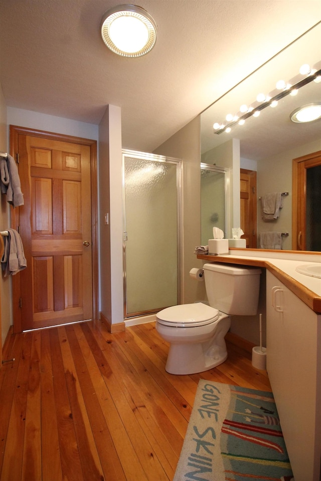 full bath with a shower stall, toilet, vanity, and hardwood / wood-style flooring